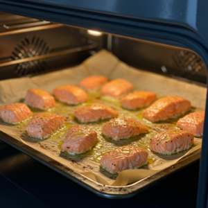 Salmon bites baking in the oven, turning golden and crispy.