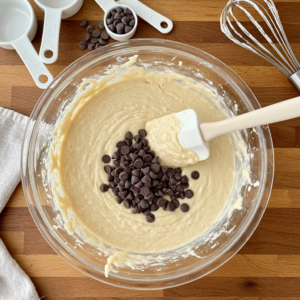 Chocolate chip waffle batter being mixed in a bowl with a spatula.