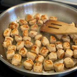 Seared chicken pieces in a pan, cooked to golden brown perfection.