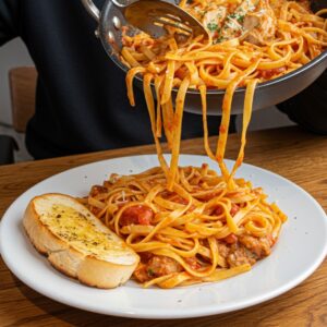 A serving of Marry Me Chicken Pasta with garlic bread and wine.