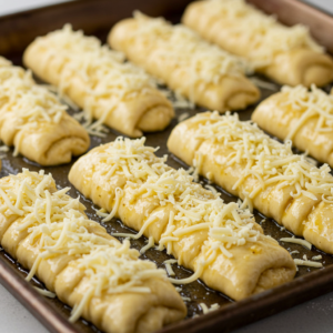 Unbaked cheese breadsticks with garlic butter and shredded cheese